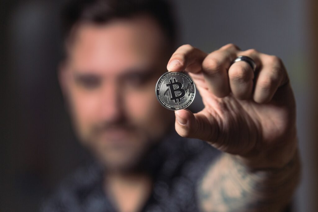 Лице, което държи сребърна монета Bitcoin