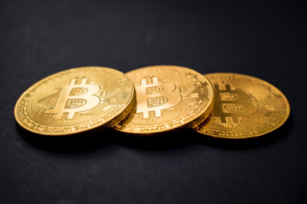tre guldfärgade bitcoins på svart yta